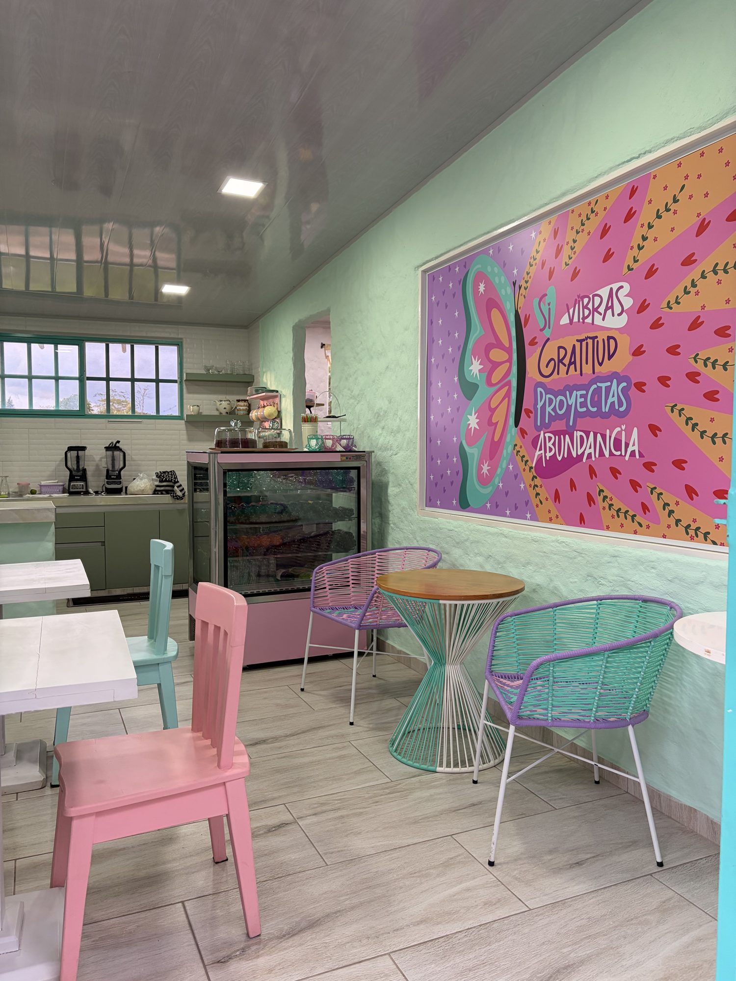 Interior de un café en El Pueblito con mural colorido y sillas pastel