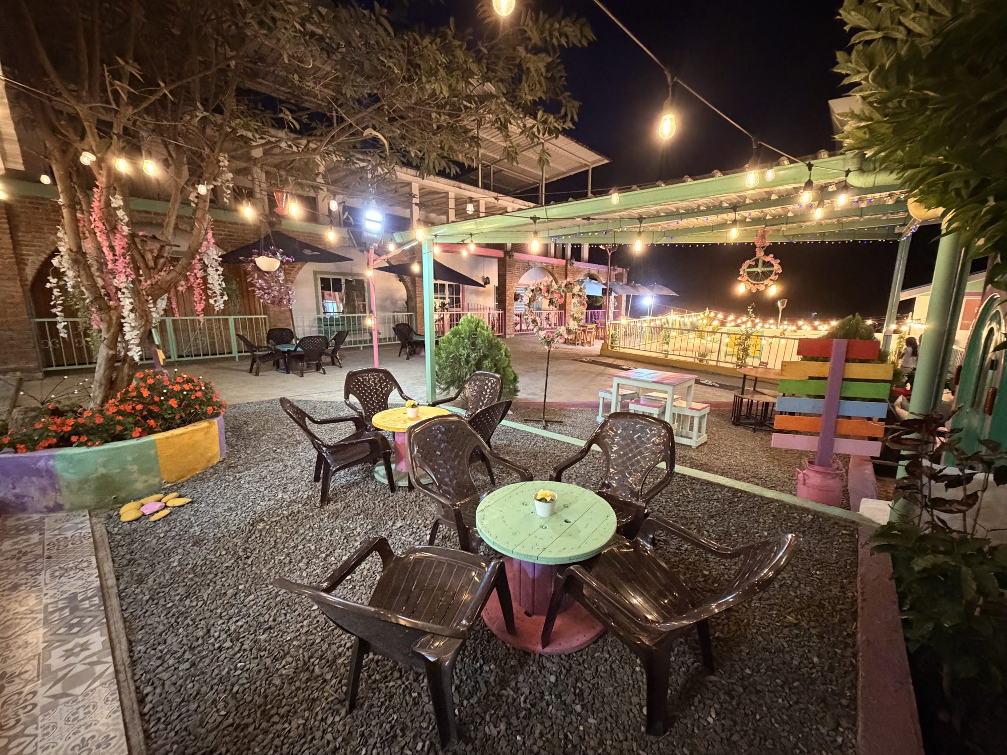 Plazoleta de El Pueblito iluminada de noche con mesas al aire libre