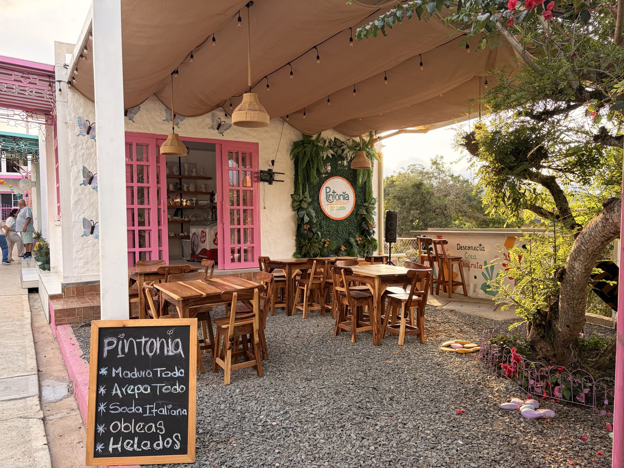 Terraza de El Pueblito de día con mesas de madera y vegetación