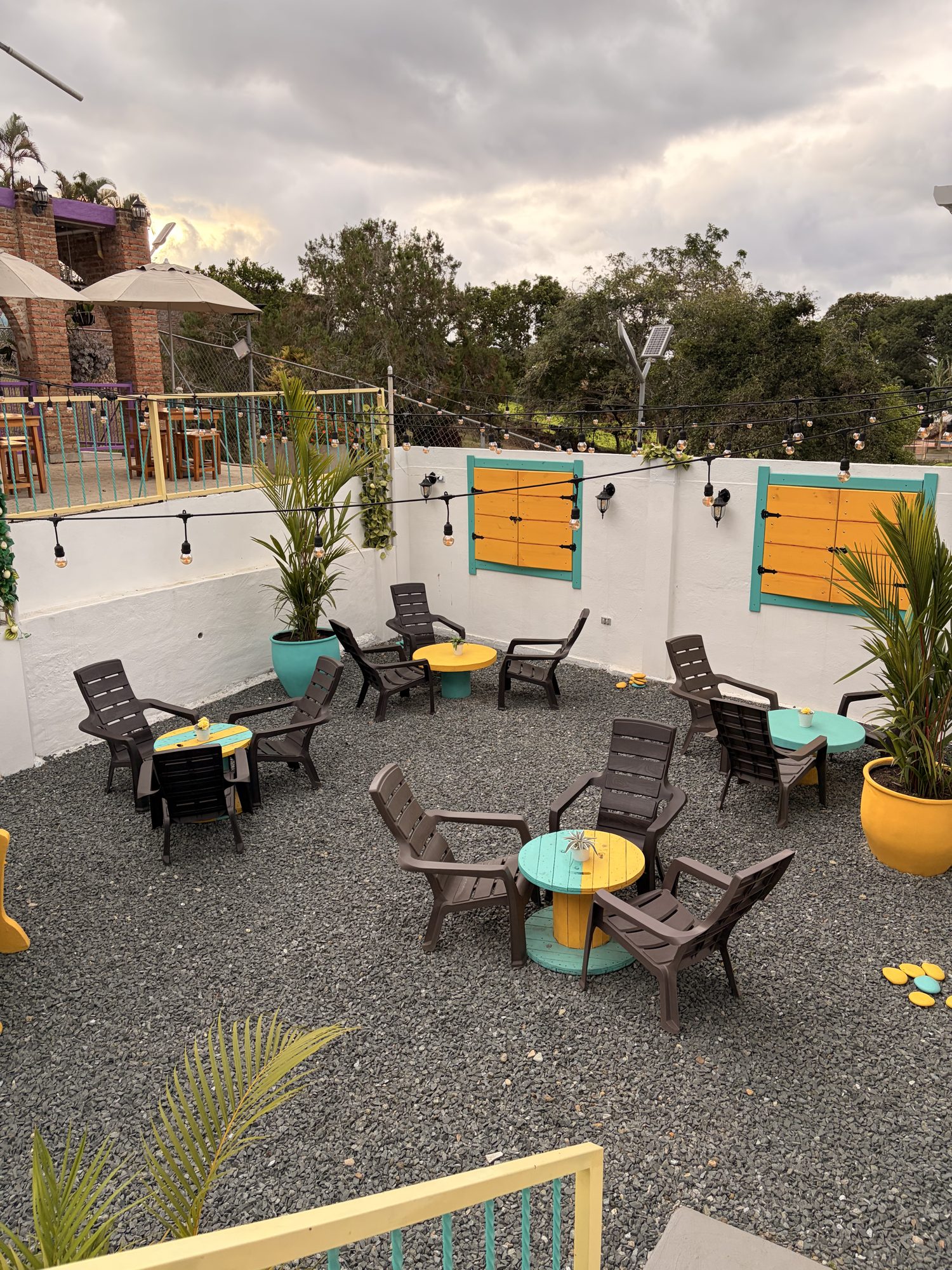 Zona exterior de El Pueblito con sillas y mesas de colores entre plantas